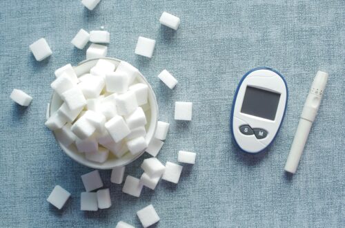 Overhead shot of a glucometer and sugar cubes representing diabetes management and sugar intake.