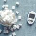 Overhead shot of a glucometer and sugar cubes representing diabetes management and sugar intake.