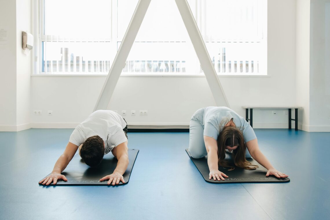 Two individuals practicing yoga in a modern clinic setting, focusing on relaxation and sciatica exercises