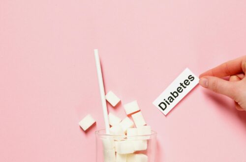 Glass of sugar cubes with diabetes label on pink background. prediabetes vs diabetes