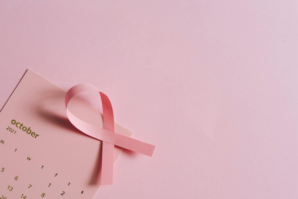 Breast cancer awareness concept with a pink ribbon on a pink October calendar.